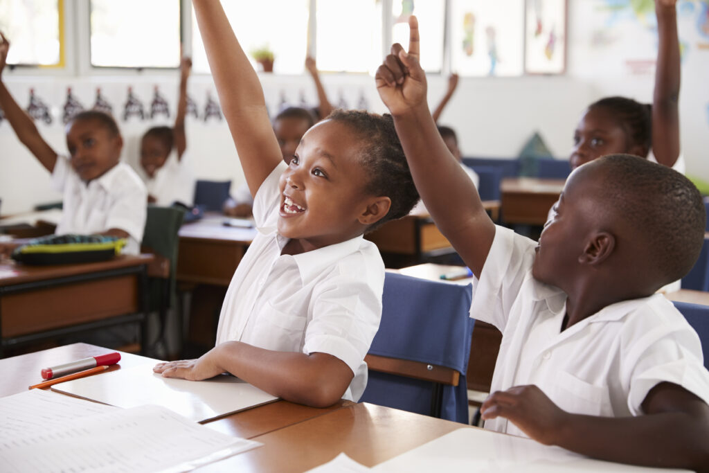 Kids raising hands during elementary school lesson, close up Elève en classe @monkeybusiness